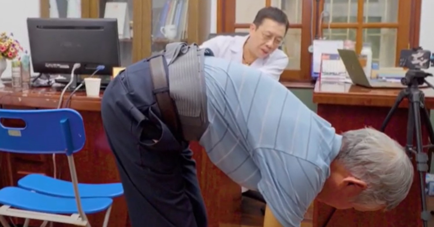 Lão Tuấn đánh giá tầm vận động của bệnh nhân Nhâm Quang Thám qua động tác cúi gập người 